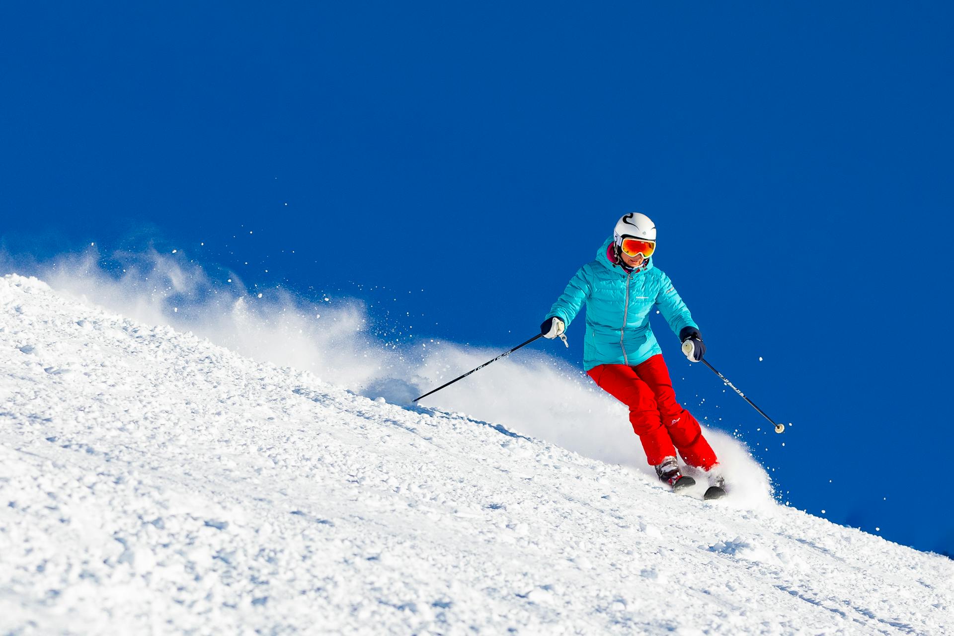 A skier carving down a beautifully groomed mountain resort slope